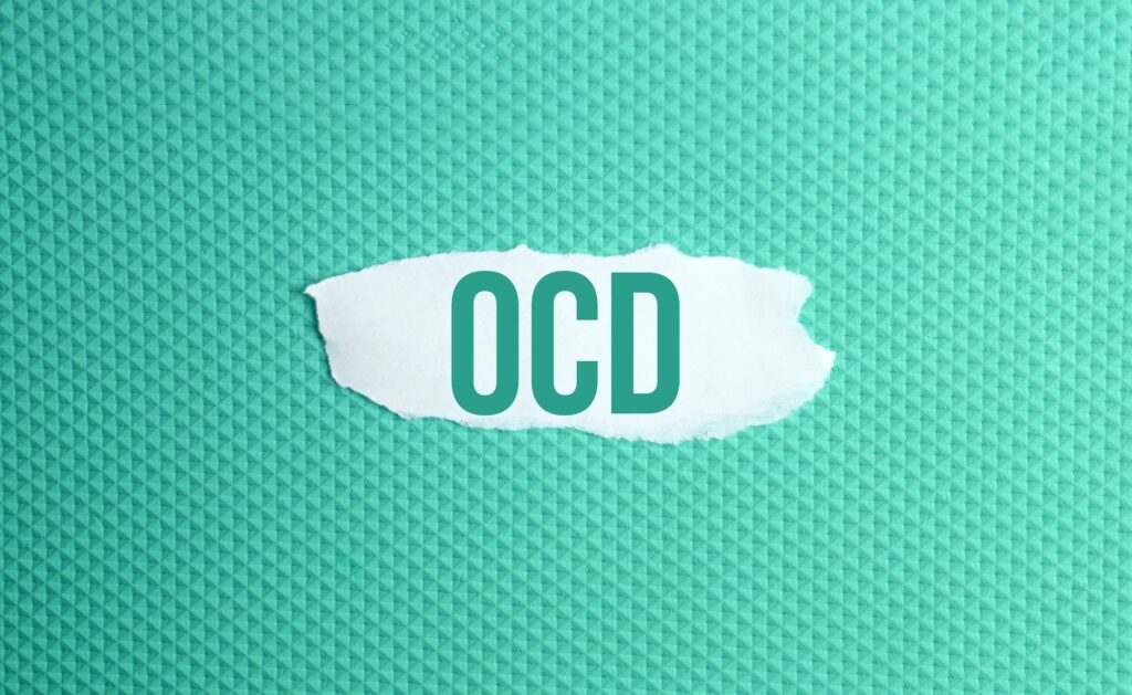 Obsessive-compulsive disorder. a torn paper written with inscription OCD on a green background